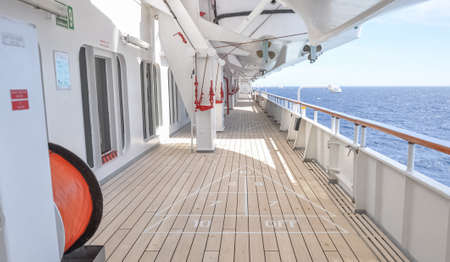 Promenade deck of a cruise ship navigating in the middle of the sea.