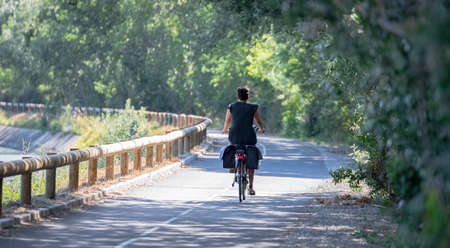 View of a woman on a cycle path by bicycle.の写真素材