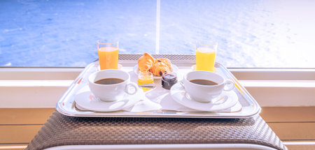 Cups of coffee and breakfast on the terrace of a balcony cabin of a cruise ship, overlooking the sea.の写真素材