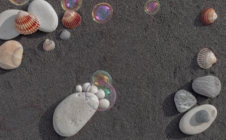 Sea sand grains background, black fine beach sand. Pebbles in the shape of a small foot to announce a birth.の写真素材