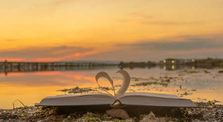 Zen on the beach. Folded book in the shape of a heart with sunrise.の写真素材