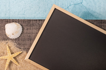 Slate board without inscription seen from above on a wooden paving above a swimming pool with a starfish. Holiday atmosphere in summer.の写真素材