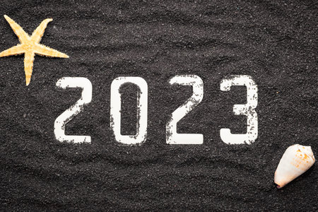 Happy new year 2023 concept with seashell and starfish on black beach sand. Winter vacation in the sun.の写真素材