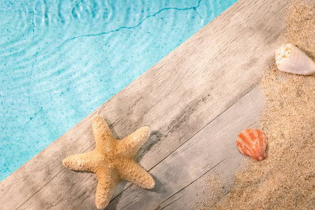Seashells seen from above on a wooden paving above a swimming pool with a starfish. Holiday atmosphere in summer.の写真素材