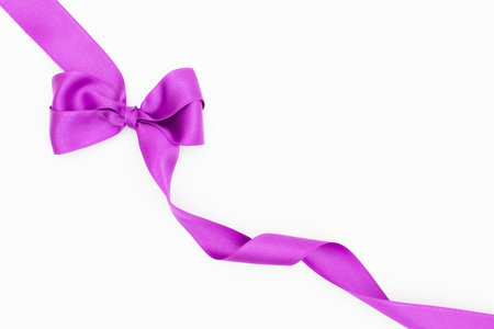 Satin ribbon bow for gift package in purple color, isolated on white background. Background with ribbon bow on white background.の写真素材