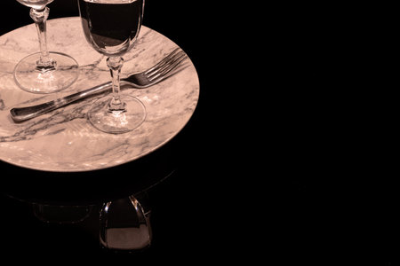 Two wineglasses on a black and white marble background with reflectionの写真素材