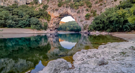 Landscape of a beautiful natural rock arch with reflection in the lake in Vallon Pont d'Arc, ArdÃ¨che, France.の写真素材