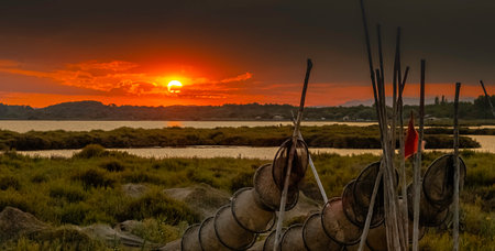 Sunset on a pond in Camargue with fishermen's nets and a beautiful sky, panoramic view.の写真素材