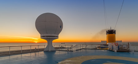 Satellite dish on the deck of a cruise ship at sunset.の写真素材
