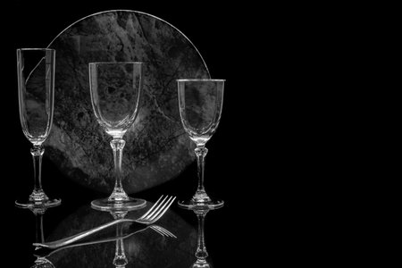 Two empty wine glasses and cutlery on a black background.の写真素材