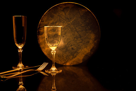 Wine glass and cutlery on a black background with reflectionの写真素材
