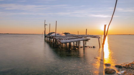Sunset on the beach with a wooden jetty in the foregroundの写真素材