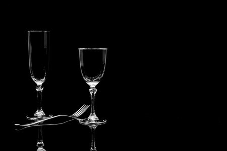 Two empty wine glasses and cutlery on a black background.の写真素材