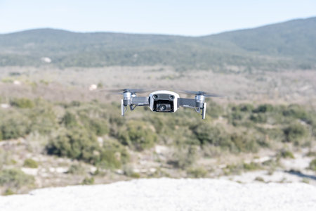 drone flying in the blue sky with blurred mountains in the backgroundの写真素材