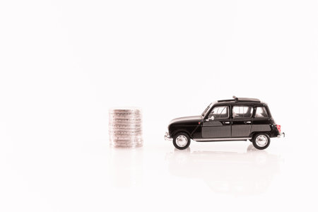 Miniature car with stack of coins on white background, business conceptの写真素材