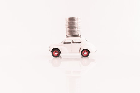 Toy car and coins on a white background. The concept of savings.