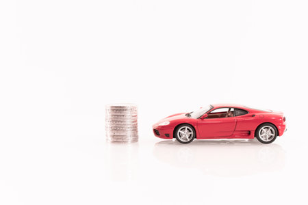 Red car with stack of coins isolated on white background with clipping pathの写真素材