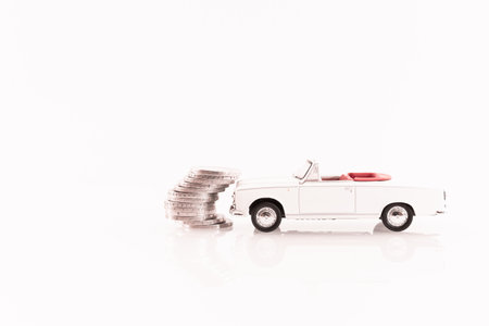 Miniature toy car with coins on white background. Business and finance concept.の写真素材