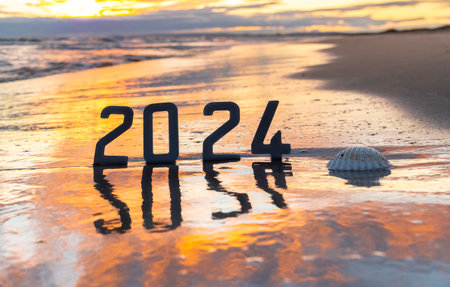 2024 new year written on the sand with seashell at sunset.の写真素材