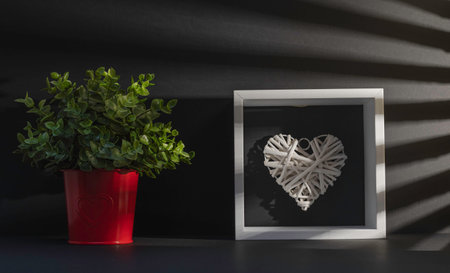 Valentines day background. White heart in red vase and black frame on black background.