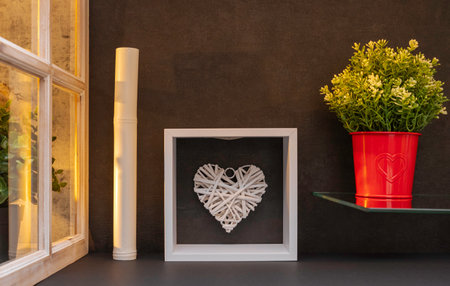 White heart in a frame on the background of a black wall.