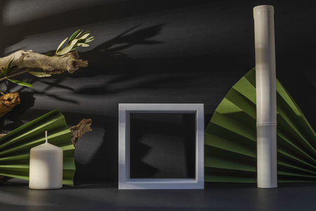 Mockup of black and white photo frame, candle and palm leaves on dark backgroundの写真素材
