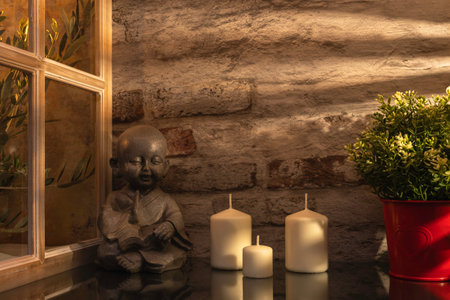 Candles and a buddha statue in front of a brick wallの写真素材