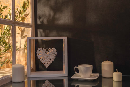 Cup of coffee with heart shaped frame and candles on black backgroundの写真素材