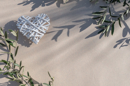 White heart with olive branch on sand background. Valentines day conceptの写真素材