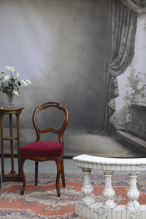 typical old photostudio with chair, table, flowers and a marble balustradeの写真素材