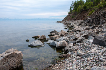 Lake Baikal shore with boulders and mountains on the horizon