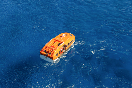Orange rescue boat on blue sea waves background. Aerial viewの写真素材