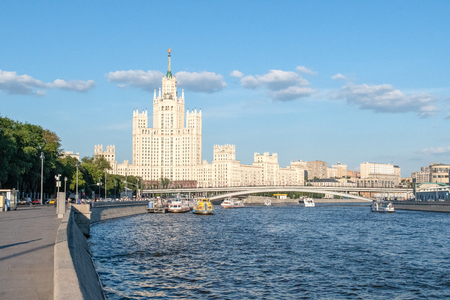Stalin's high-rise and the bridge over the Moscow river against the blue sky and a chain of clouds. Summer city landscape, pleasure boats on the wavy waterの写真素材