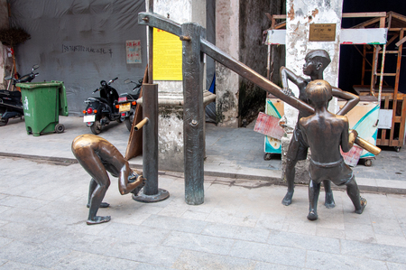 BEIHAI, CHINA - JUN, 2013: Street bronze sculpture of boys bathing from the water pipe on the old street in Beihai, China.のeditorial素材