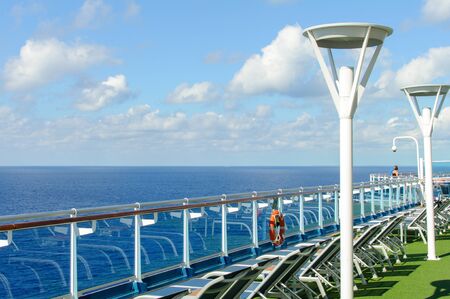 View from the deck of a cruise ship in the ocean. Seating area for passengers, chairs and sun loungers. Sunbathe.の写真素材