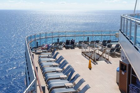 View from the deck of a cruise ship in the ocean. Seating area for passengers, chairs and sun loungers. Sunbathe.の写真素材