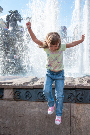 MOSCOW, RUSSIA - AUGUST, 2011: The heat in the city. A little girl posing at a fresh fountain in the city Park in hot summer weather.のeditorial素材