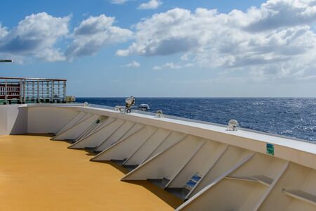 Yellow deck of the ship with a fence against the blue sea and cloudy sky over the horizon.の写真素材