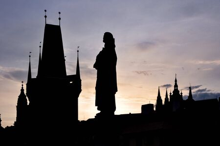 PRAGUE, CZECH - MAY 2009: Silhouette of a historical sculpture on the Charles bridge against the towers of the old townのeditorial素材