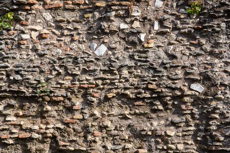 A fragment of the original masonry of raw stones built by ancient Rome. Background. Pattern. Ocher, brown.の写真素材