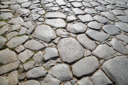 A fragment of the original cobblestone pavement of time-worn stones built by Ancient Rome. Background. Pattern. Gray.の写真素材
