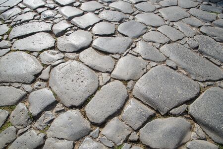 A fragment of the original cobblestone pavement of time-worn stones built by Ancient Rome. Background. Pattern. Gray.の写真素材