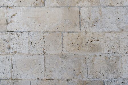 Fragment of an old stone wall of an ancient Roman temple made of processed sandstone. Background. Gray.