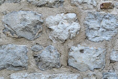A fragment of an old stone wall made of rough stones. Background. Gray.の写真素材