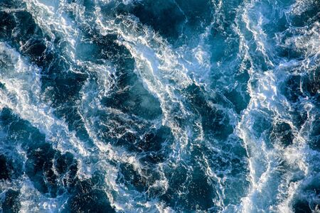 Seething waves with foam backlit by the setting sun. Transparent. Navy blue. Blue. Background. Pattern.の写真素材