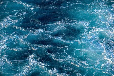 Seething waves with foam backlit by the setting sun. Transparent. Navy blue. Blue. Background. Pattern.の写真素材