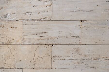 A fragment of the wall of the ancient temple in the Acropolis, built of smooth marble slabs. Background. Yellow-beige color.の写真素材