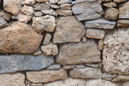 A fragment of an old stone wall made of rough stones. Background. Ocher. Gray.の写真素材