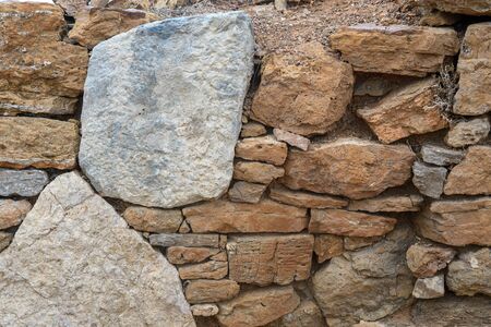 A fragment of an old stone wall made of rough stones. Background. Ocher. Gray.の写真素材
