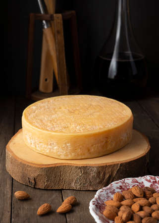Moody brazilian Canastra artisanal cheese and almonds over a wooden board with wine bottleの写真素材